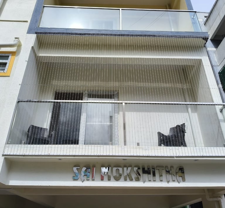 Close-up of sleek invisible grills installed on a balcony overlooking a Chennai skyline at sunset.