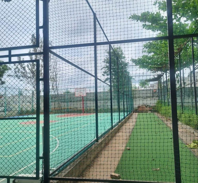Workers carefully fitting sports nets on a rooftop terrace under a clear blue sky.