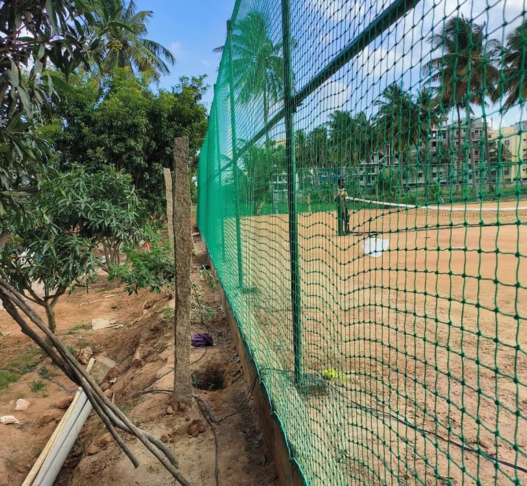 Terrace top nets casting shadows over a quiet home practice area in the evening light.