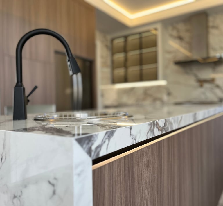 Modern luxury kitchen island featuring white marble countertops and a sleek matte black faucet.
