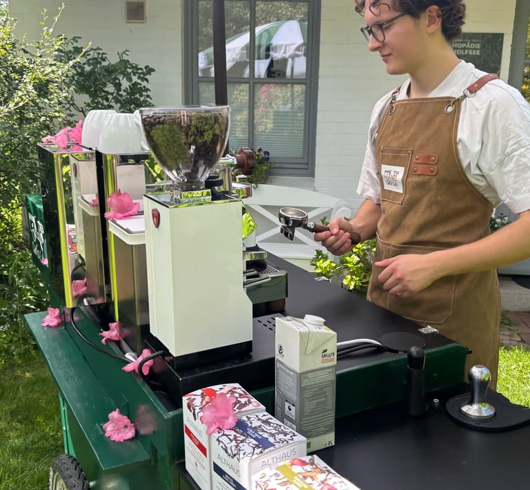 Barista mit Schürze bereitet Kaffee mit Siebträger an Kaffeemühle zu.