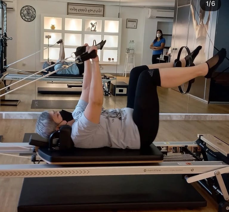 Client performing reformer arm and leg coordination exercise under the guidance of instructor Maalz