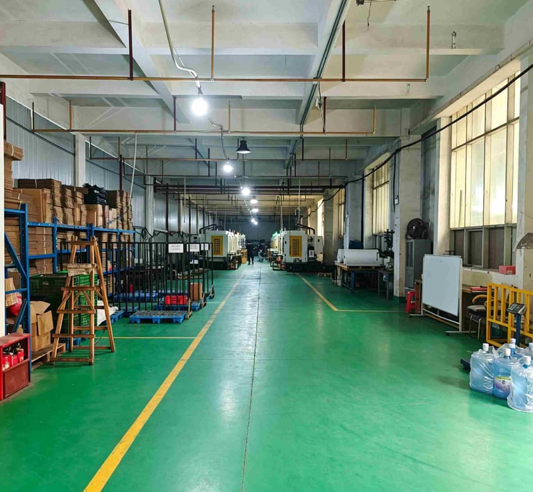 Industrial manufacturing facility with green floors, injection molding machines, and organized storage shelves.