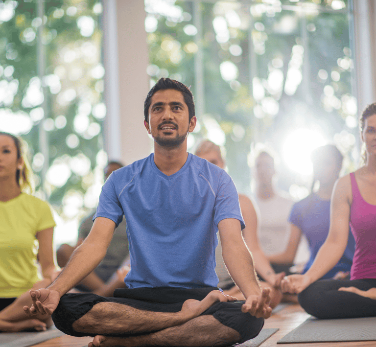 a man and a group of women doing yoga/meditating together