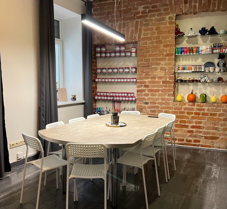 Modern meeting room with white table and chairs against an exposed red brick wall with shelving.