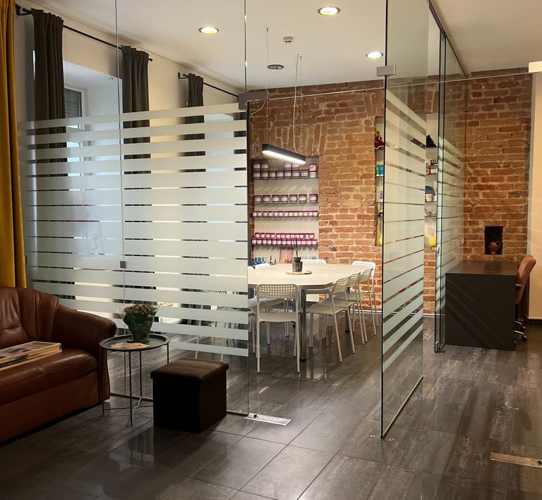 Modern office interior featuring a glass partition wall, meeting room with brick walls, and leather seating.
