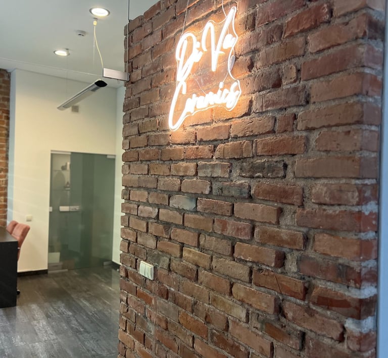 A glowing neon business sign hangs on a rustic red brick wall in a modern office interior.