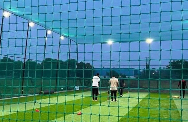 Installation team securing a large sports net at a local Bangalore cricket ground.