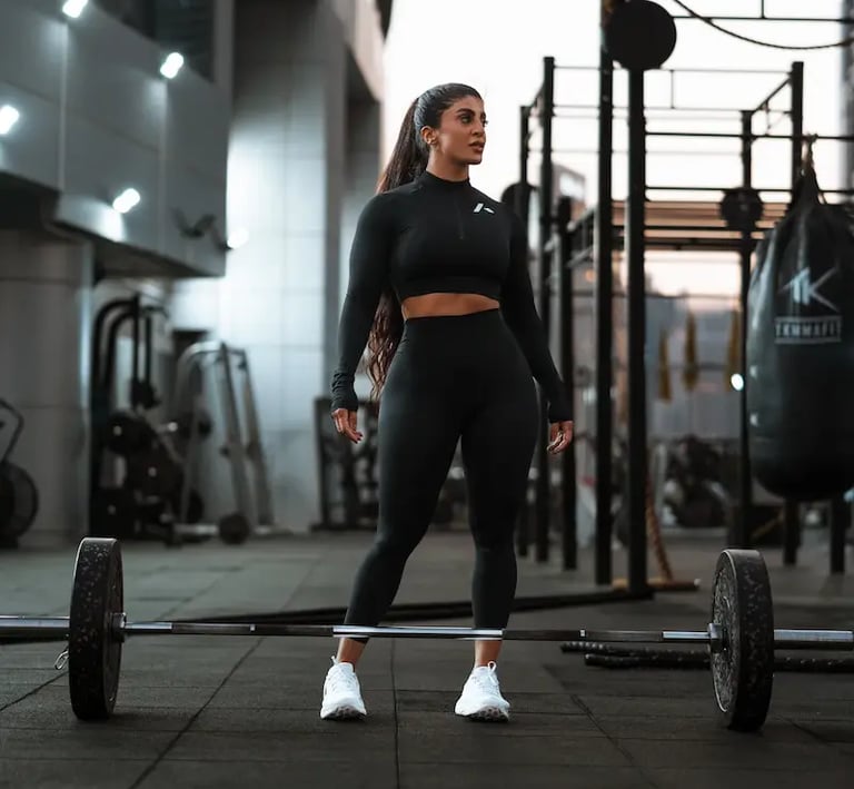 mais alhajarji wearing black sportswear standing in a gym in front of a barbell