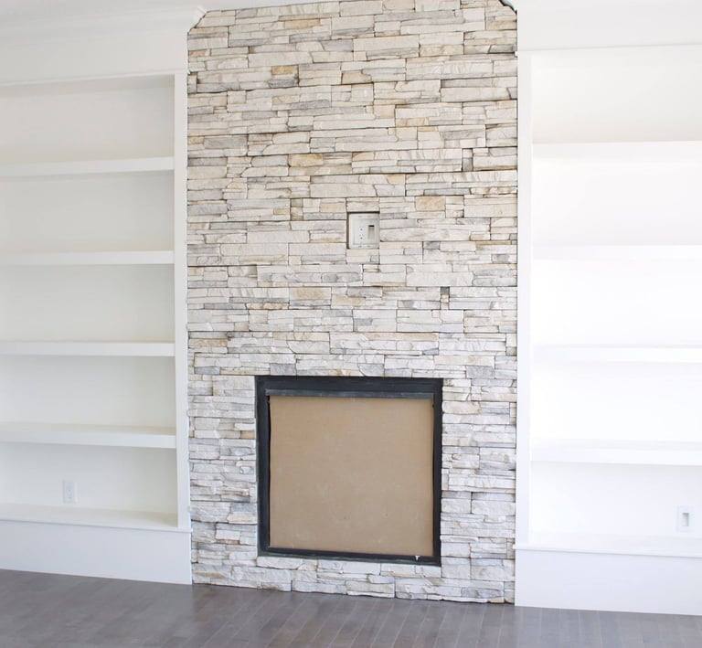 a white fireplace with stone facing and shelves