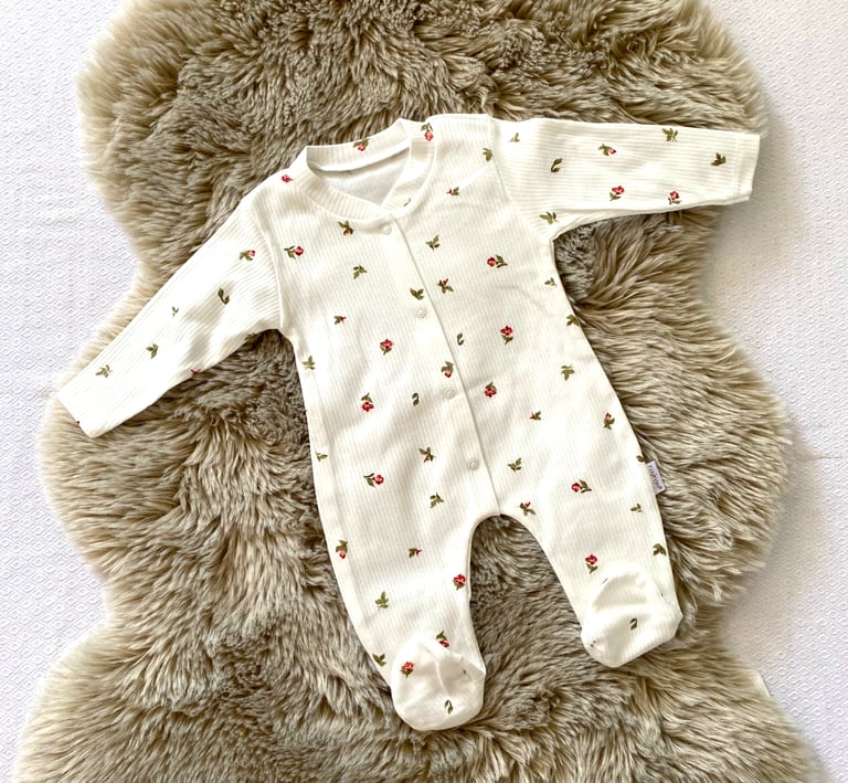 a cute baby's outfit is shown with flowers, colors are bright and beautiful