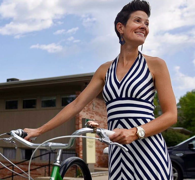 Woman in striped dress standing with bike