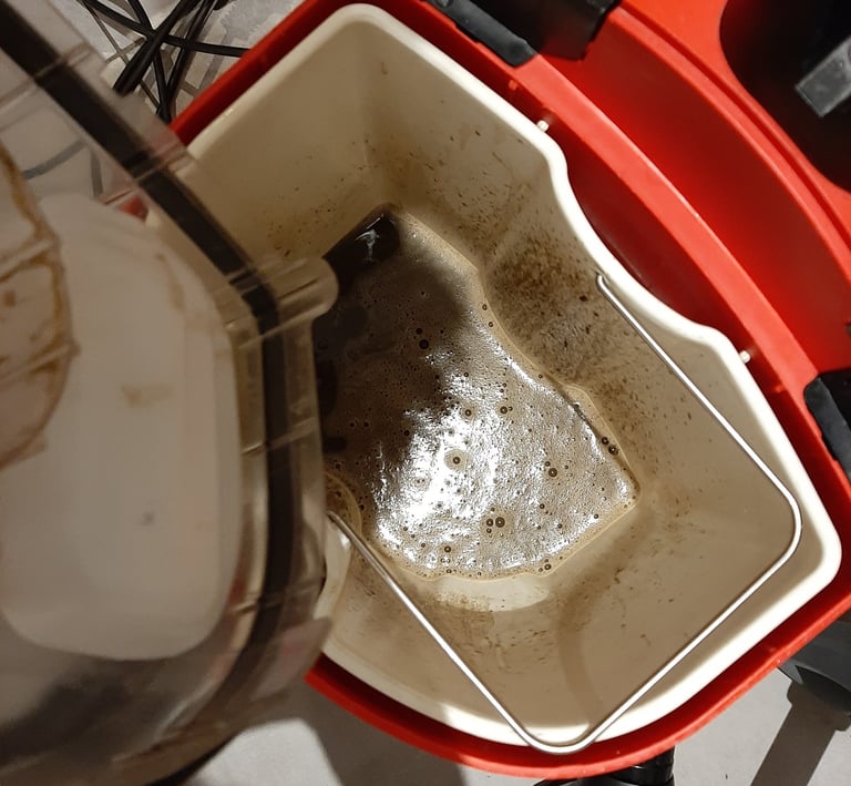 Eau d’extraction très sale dans un seau après le nettoyage professionnel d’un canapé