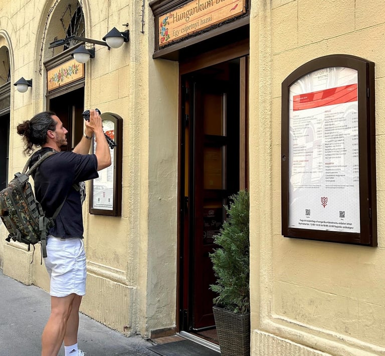 Turista fotografiando la entrada y el menú exterior del restaurante Hungarikum Bisztró en Budapest, 