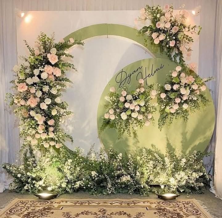 a wedding ceremony with a large green circle with flowers
