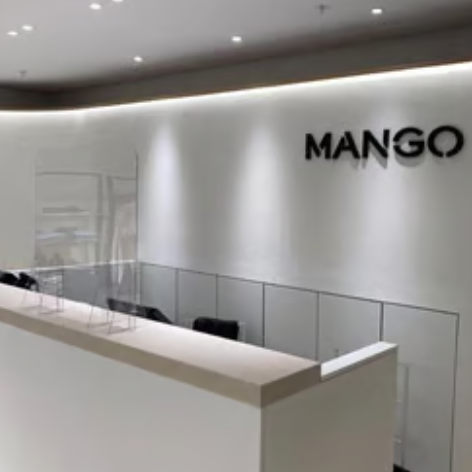 Minimalist interior of the Mango retail store, featuring microcement, a white checkout counter, and