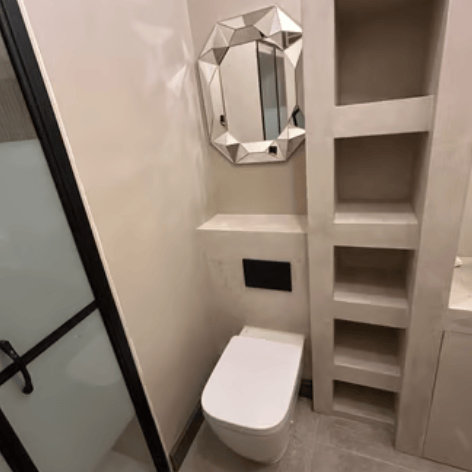 A modern bathroom with a private nook in textured beige, finished in microcement
