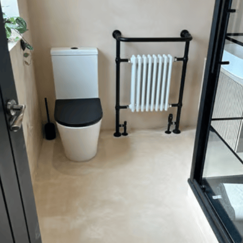 Modern bathroom with microcement walls, white toilet, black seat and black designer heated towel rai