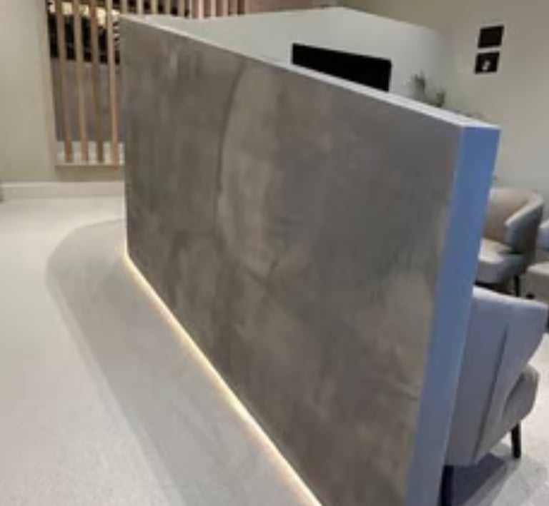A modern waiting room featuring a private, textured grey alcove finished in microcement, with recess