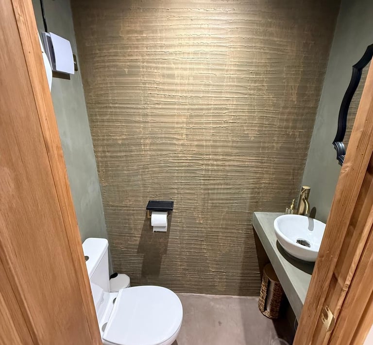 Rustic modern bathroom featuring a white vessel sink, gold faucet, and ornate black mirror.