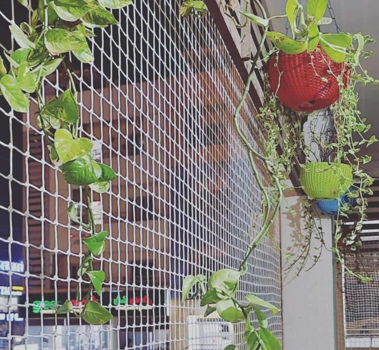 Evening shot of a balcony protected by pigeon nets with city lights of Bangalore in the background.