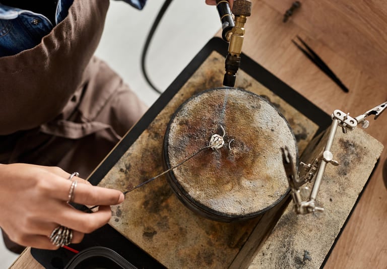 Un joyero utiliza un soplete de soldadura para elaborar un anillo de plata personalizado.