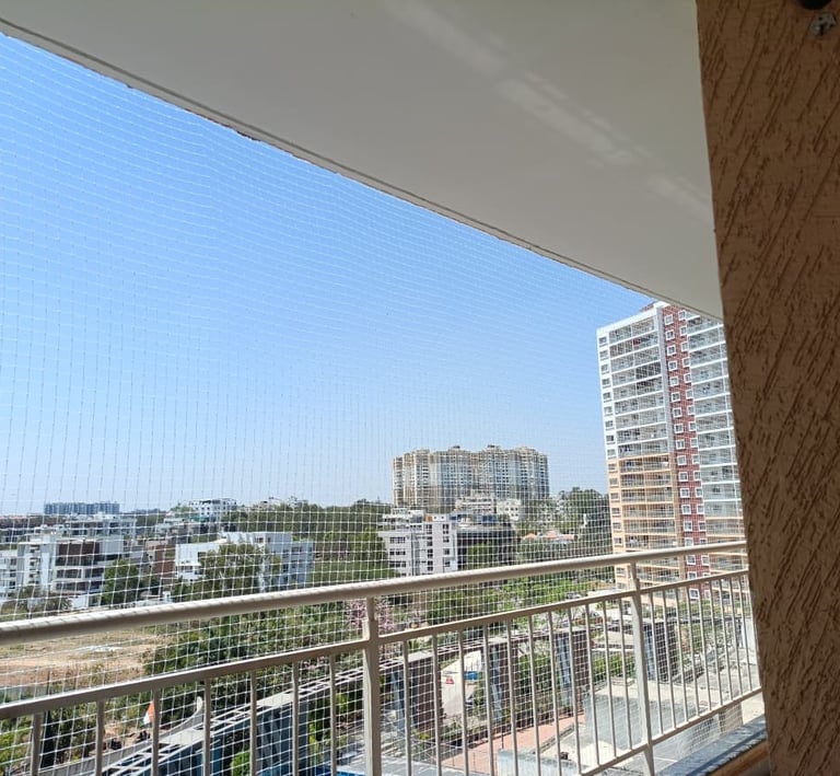 Wide shot showing a high-rise balcony fully covered with a transparent safety net against the Mumbai