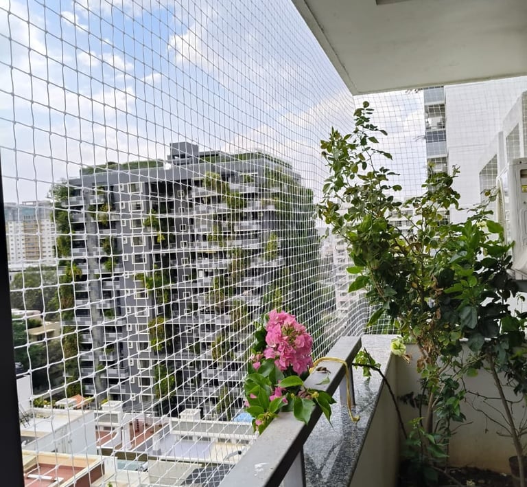 Wide shot of a Bandhup West balcony fully covered with a sturdy pigeon net, sunlight filtering throu
