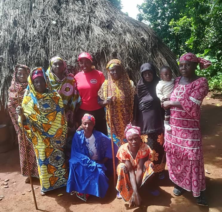 a group of people standing around a hut with a thatched roof