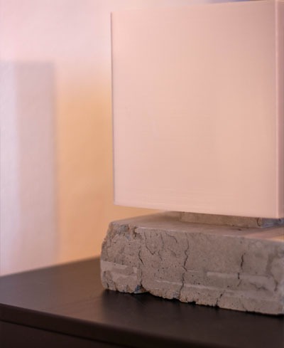 Modern square table lamp with a minimalist white shade and a rustic gray concrete base on a dark surface.