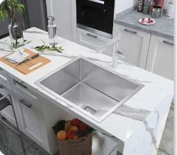 Modern stainless steel undermount kitchen sink installed in a white marble waterfall island countertop.