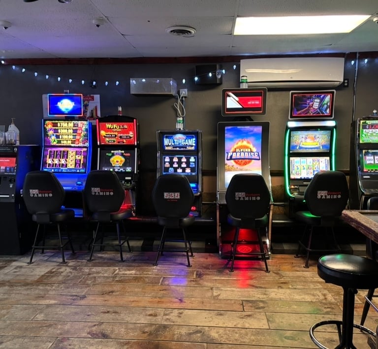 Video gaming terminal slot machines lined up inside a bar with wood floors and neon lights.