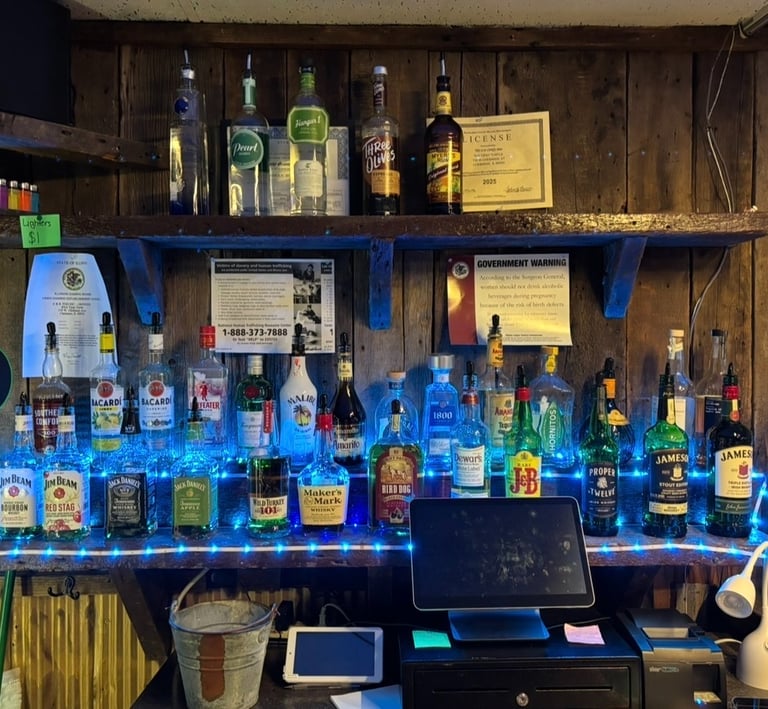 Rustic wooden bar shelves stocked with liquor bottles like Jameson and Bacardi under blue LED lights.