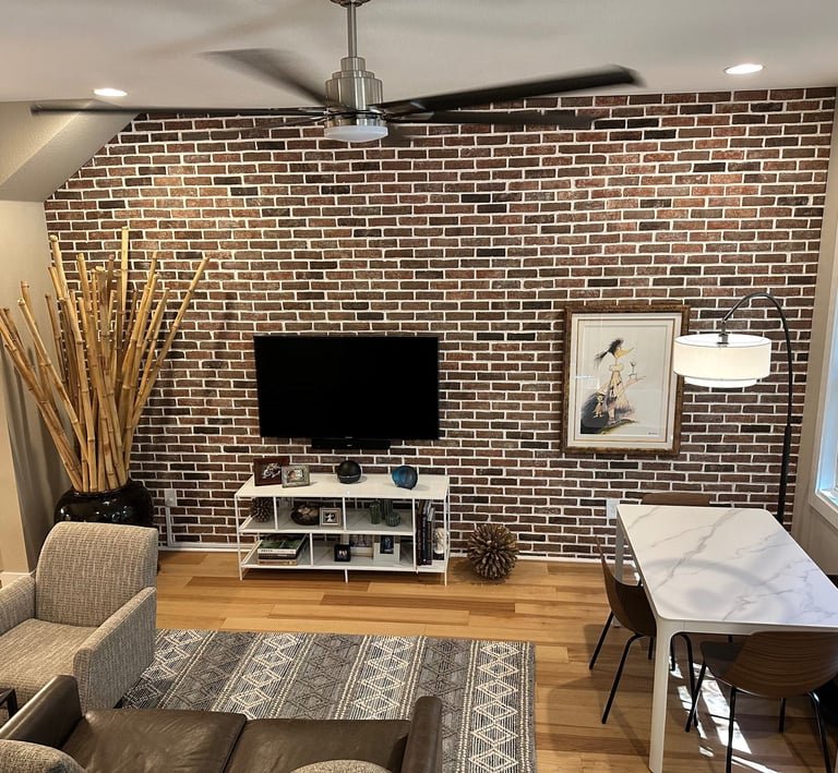 Modern living room featuring a rustic thin brick accent wall, wall-mounted TV, and hardwood floors.