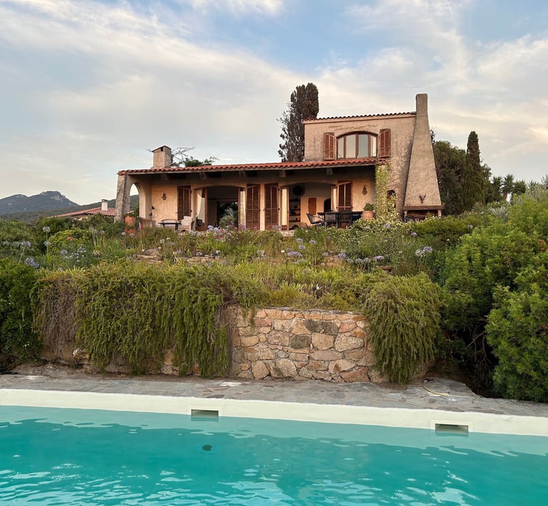 Luxury Mediterranean villa with a private swimming pool and lush garden landscape in Sardinia.