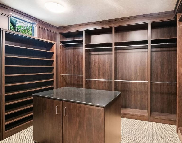 Spanish Trails walk-in closet w/dark wood custom cabinetry w/center island granite countertop.