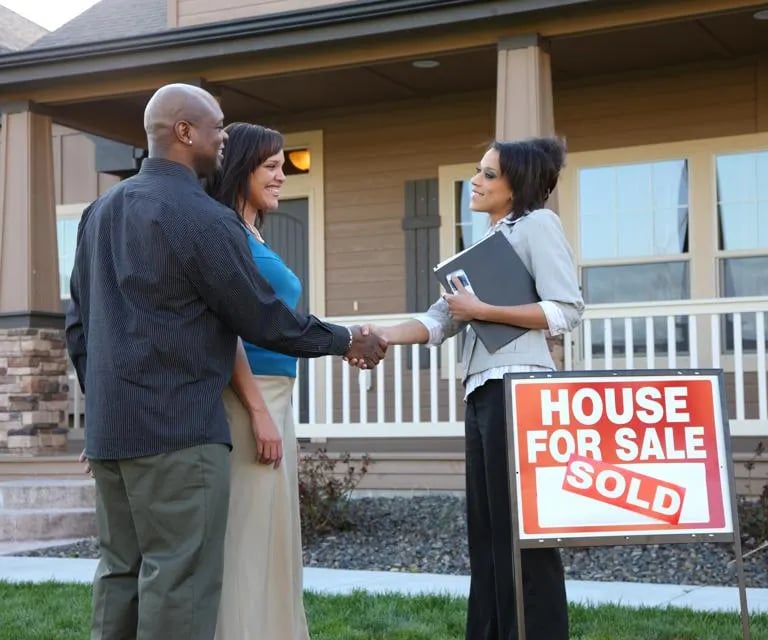 A man and woman shaking hands in front of a house