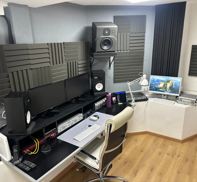 recording music studio with a computer monitor, speakers, and a laptop