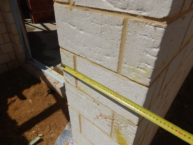 Close-up of Perth building inspector checking brickwork defects and Australian Standards references