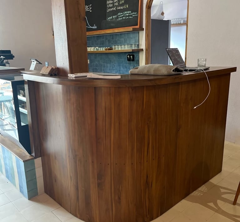 a bar counter with a wooden bar stool and a chalkboard