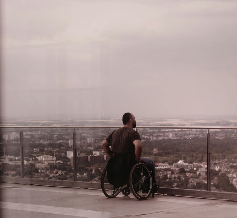 ein Mann im Rollstuhl, der auf eine Stadt blickt