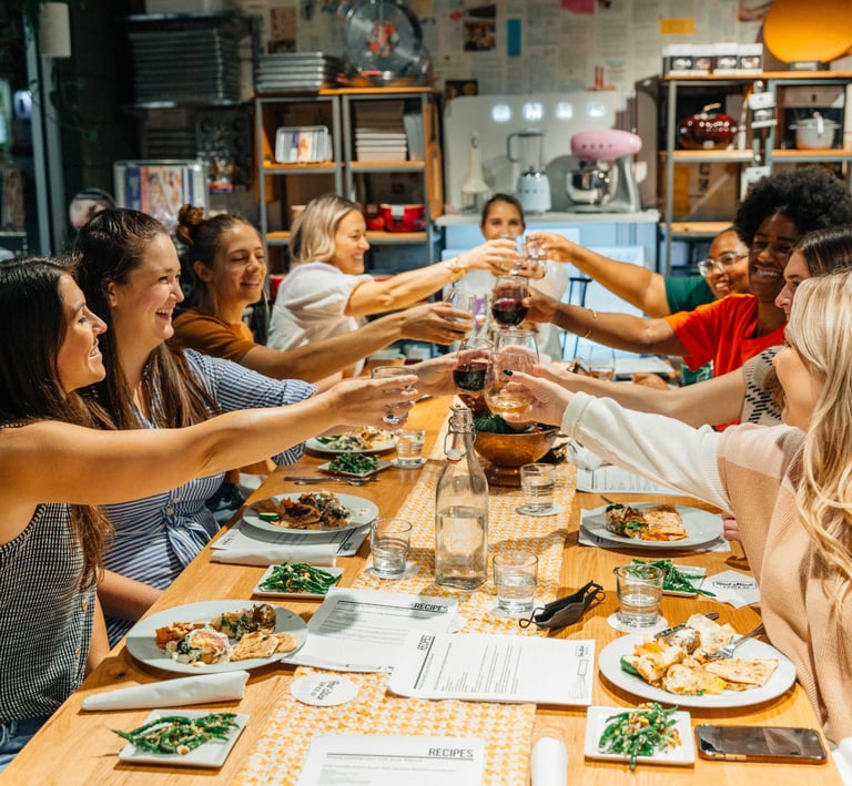 Corporate team clinking glasses at the dinner table during a celebratory team-building retreat
