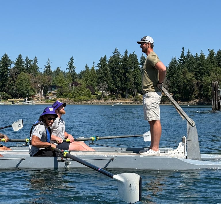 Team rowing on the water with a coach guiding them during a leadership and team-building event