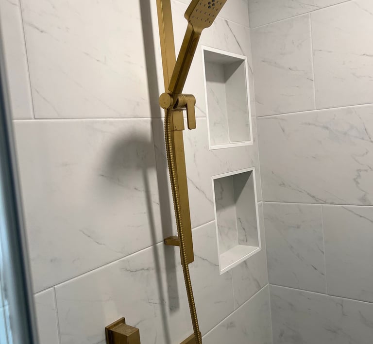 Modern bathroom shower featuring brushed gold fixtures on white porcelain tiles.