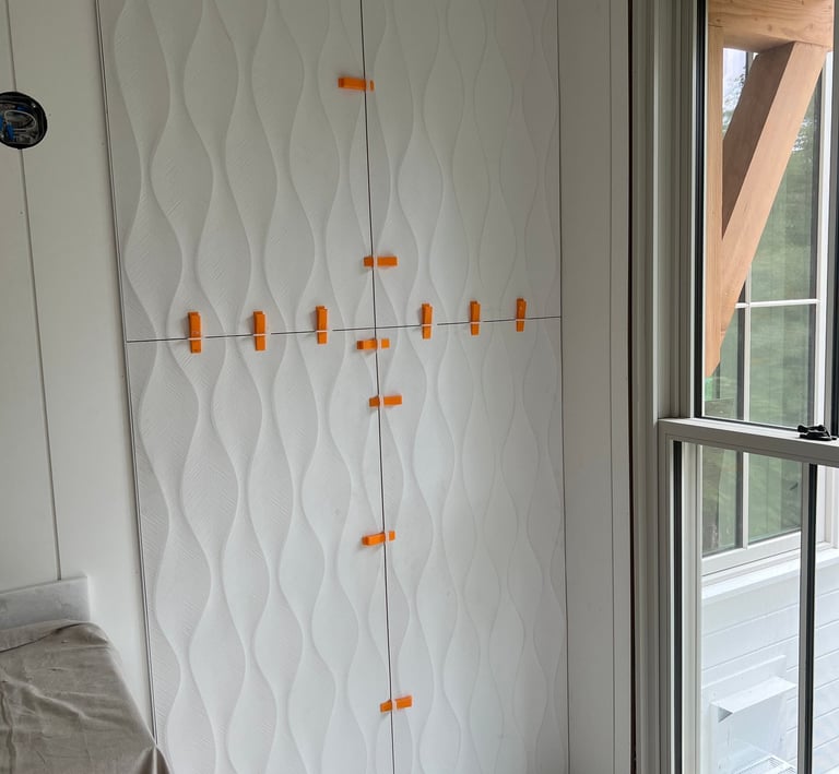 Installation of white 3D textured wave wall tiles using leveling spacers in a bathroom.