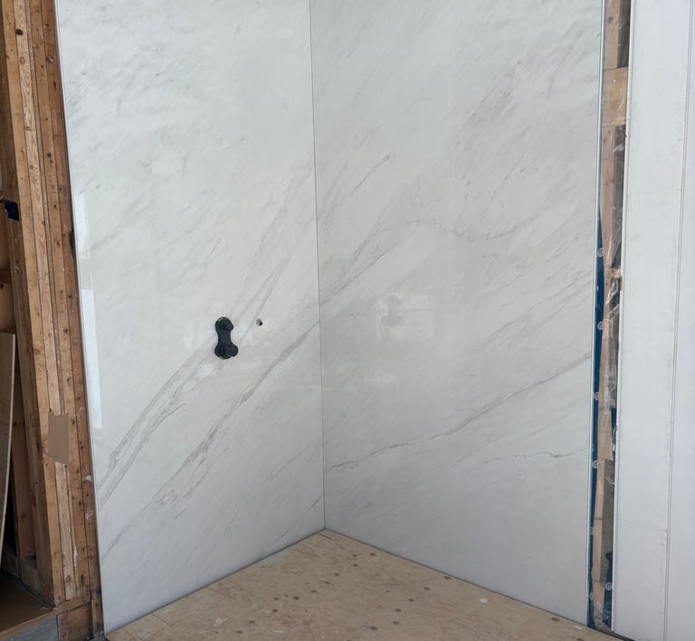 White marble pattern porcelain slab wall panels installed in a bathroom shower.