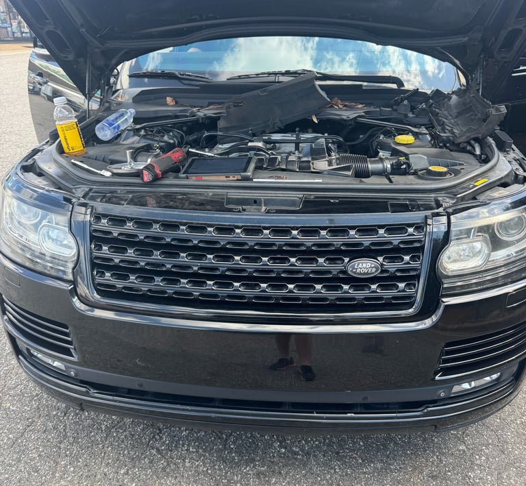 Black Land Rover Range Rover with an open hood undergoing engine repair and maintenance.