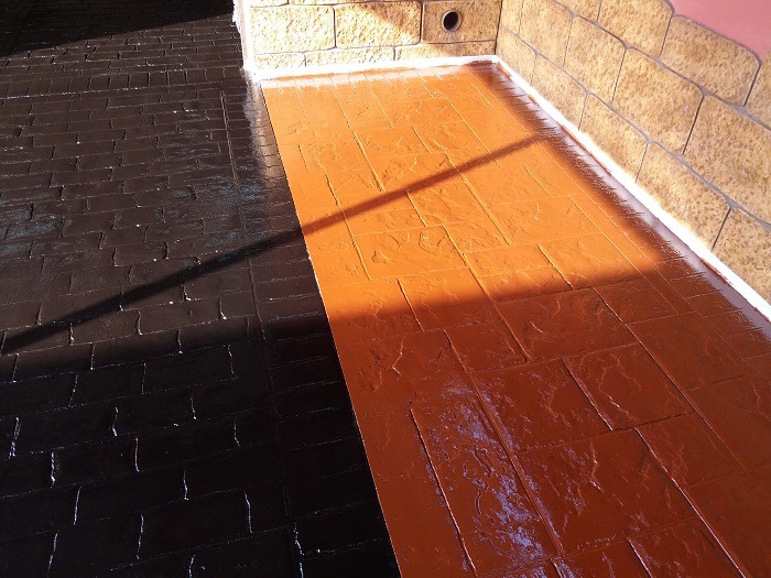 Superficie de hormigón impreso con acabado en resina de dos colores, ideal para crear contraste en áreas exteriores.