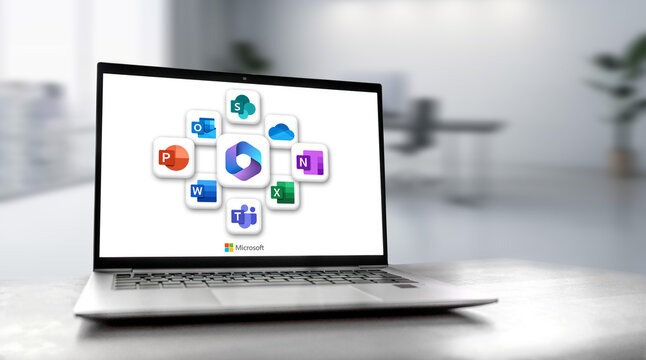 Laptop on desk displaying Microsoft 365 dashboard with Office app logos on screen.