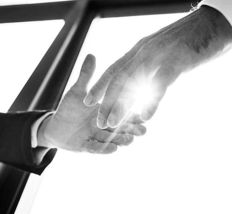 Dos manos a punto de estrecharse con un halo de luz en medio de ambas.